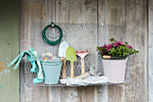 Drahtregal mit Gartenwerkzeugen und Blumentopf an Holzwand