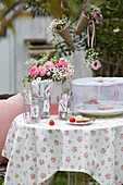 Romantische Gartentafel mit floraler Tischdecke und Rosenarrangement