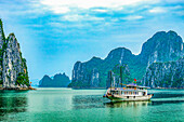 Ha Long Bay, Vietnam. Wide angle landscape view of tourist boat among the limestone karsts and islets of the UNESCO Heritage Site.