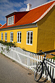 Skagen, Denmark. Bike, yellow house with white picket fence and terra cotta roof. (Editorial Use Only)
