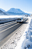 Auto fährt auf vereister Straße in Richtung St. Moritz und schneebedeckte Berge im Winter, Bever, Kanton Graubünden, Schweiz
