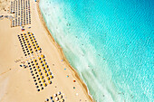 Sonnenschirme und Liegen am weißen Sandstrand von Falassarna mit Blick auf das kristallklare Meer, Luftaufnahme, Insel Kreta, Griechenland