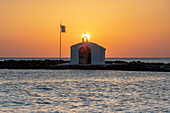 Sonnenaufgang über der ikonischen griechischen Kapelle mit Blick auf das raue Meer, Georgioupolis, Insel Kreta, Griechenland