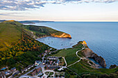 Luftaufnahme von Lulworth Cove bei Sonnenuntergang mit Booten, Durdle Door, Dorset, Vereinigtes Königreich, Nordeuropa