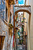 Charakteristische enge Gasse zwischen hohen Gebäuden mit Stützbögen zwischen den Häusern. Vico del Gargano, Provinz Foggia, Apulien, Italien