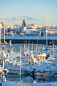 Blick auf Boote im Jachthafen von Hafnarfjorour und die Stadt im Hintergrund im Winter, Hafnarfjorour, Island