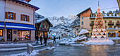View of shops, town centre and snow covered mountains in Courmayeur at dusk during Christmas, Courmayeur, Aosta Valley, Italian Alps, Italy