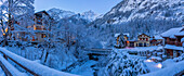 View of chalets and snow covered mountains in Courmayeur before dawn in winter, Courmayeur, Aosta Valley, Italian Alps, Italy
