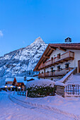 View of chalets and snow covered mountains in Courmayeur before dawn in winter, Courmayeur, Aosta Valley, Italian Alps, Italy