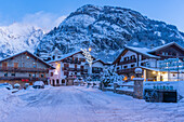 View of chalets and snow covered mountains in Courmayeur before dawn in winter, Courmayeur, Aosta Valley, Italian Alps, Italy