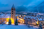 Church of Saint Pantalon, snow covered town centre and mountainous background in winter at dusk, Courmayeur, Aosta Valley, Italian Alps, Italy