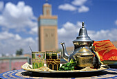 Tea set with the minaret of Al Mansour Mosque in the background, Marrakech, Morocco