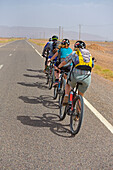 Electric mountain bikers on road from Tamegroute toward the South (N 9), Draa River valley, Province of Zagora, Region Draa-Tafilalet, Morocco