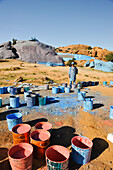 Painter working on Painted Rocks site, work of the Belgian artist Jean Verame, around Tafraout, Anti-Atlas, Morocco