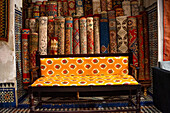 Stacks of vibrant handwoven Moroccan rugs and carpets displayed in a traditional shop in Fes, Morocco