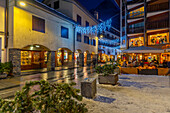 View of restaurants and bars on via Roma at dusk, Courmayeur, Aosta Valley, Italy