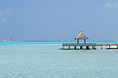 Pier and the clear waters of the lagoon on an exotic Island in The Maldives, Indian Ocean