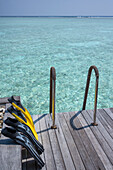 Flossen zum Trocknen auf einem Deck mit Blick auf eine kristallklare Lagune auf einer exotischen Insel der Malediven, Indischer Ozean