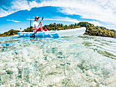 Woman kayaking in clear tropical sea, summer fun, The Maldives, Indian Ocean