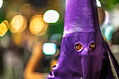 Detailreiche Darstellung eines Büßers mit Kapuze, der inmitten der lebhaften Atmosphäre der Karwochenfeierlichkeiten in Sevilla, Spanien, seine Augen konzentriert.