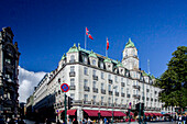 Oslo, Norway, Aug 10 2017, Grand Hotel stands prominently on Karl Johans street, with flags waving and patrons enjoying the outdoor cafe on a sunny day.