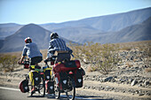 Two cycle tourists on a lonely road in the area of Death Valley, California