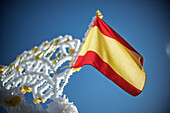 A Spanish flag waves next to an arch decorated for the Virgen del Rosario procession in Carrion de los Cespedes, Seville, Andalusia.