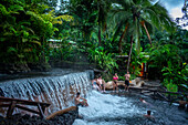 Heiße Quellen aus dem Arenal Vocano im Tabacón Grand Spa, Costa Rica. Ein Besucher genießt einen der warmen Bäche, die durch das Tabacon Hot Spring Resort and Spa in Costa Rica fließen