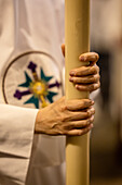 Close-up of hands holding a candle during a religious event in Seville.