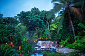 Heiße Quellen aus dem Arenal Vocano im Tabacón Grand Spa, Costa Rica. Ein Besucher genießt einen der warmen Bäche, die durch das Tabacon Hot Spring Resort and Spa in Costa Rica fließen