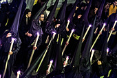 Seville, Spain, Apr 9 2009, Nazarenos in black robes carry candles through a crowded narrow street in Seville, celebrating Holy Week with solemnity and tradition.