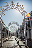 Carrion de los Cespedes street adorned with arches and colorful papers for the Virgen del Rosario procession in Seville, Andalusia, Spain.