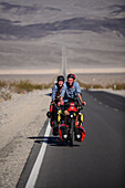 Two cycle tourists on a lonely road in the area of Death Valley, California