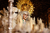Virgin of Esperanza Macarena on her float surrounded by candles during the solemn conclusion of Good Friday procession in Seville.
