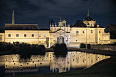 Nighttime setting of a contemporary art museum reflecting in nearby quiet waters.