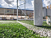 Close-up of a football goalpost on an artificial turf field in Seville, featuring the vibrant green surroundings.
