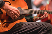 A musician skillfully plays the guitar during an evening jazz concert creating a vibrant atmosphere filled with music.