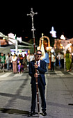 A devoted parishioner leads the procession in Castilleja del Campo by holding a crucifix, showcasing faith during the celebration.