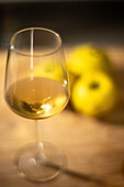 A still life showcasing a wine glass and quinces, captured with warm lighting.