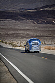 Silver Airstream camper travel trailer on an empty road in the area of Death Valley, California
