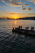 Aerial view of people enjoying the sunset from a dock in waterside Cais do Sodre, a buzzing nightlife and dining destination in Lisbon, Portugal