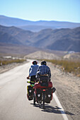Two cycle tourists on a lonely road in the area of Death Valley, California