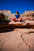 Junge kaukasische Frau sitzt mit gekreuzten Beinen auf dem Canyon Overlook Trail im Zion National Park, Utah
