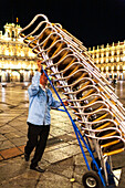 Salamanca, Spain, Aug 18 2018, Worker storing chairs at Plaza Mayor in Salamanca, Spain during nighttime scene.