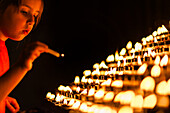 A young girl lights a candle in New Cathedral, Salamanca, creating a peaceful ambiance.