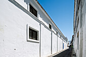 Discover the charming streets of Barrio Alto in Sanlucar de Barrameda, characterized by traditional white walls under a clear blue sky.