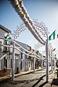 Carrion de los Cespedes street adorned with arches and colorful papers for the Virgen del Rosario procession in Seville, Andalusia, Spain.