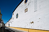 Wineries with white walls line the narrow street in Barrio Alto, Sanlucar de Barrameda, showcasing the charm of Andalusian architecture.