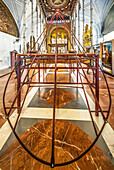 Preparing the paso de palio for Virgen del Valle inside the Church of the Annunciation in Seville, showcasing the intricate metal structure.