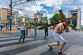 A man in a representation of Jesus Christ crosses a crosswalk on a street in Caracas.